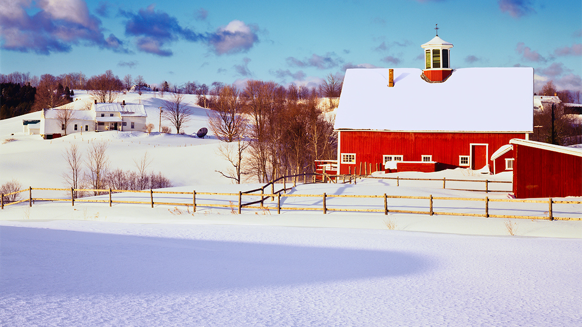 A farm barn and fields covered in deep snow.