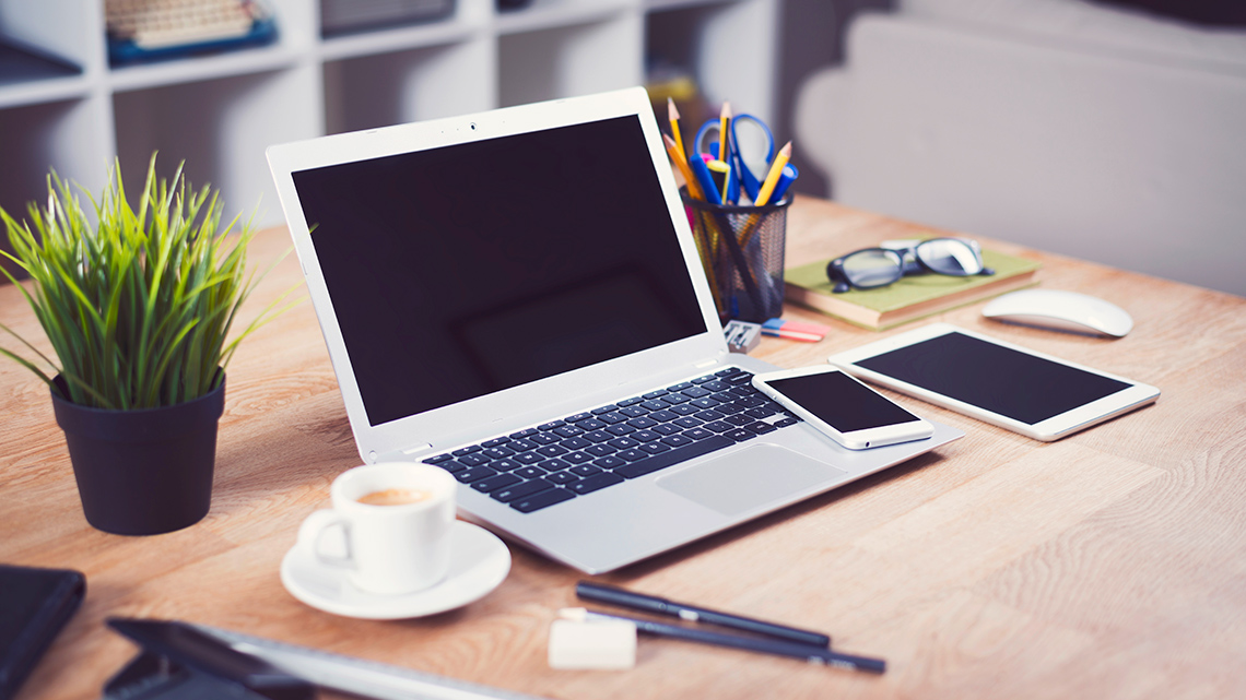 A laptop, smartphone, and tablet sitting on a desk.