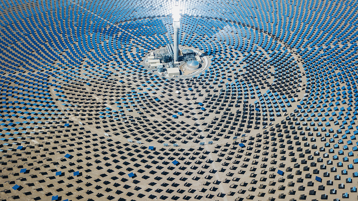 Hundreds of mirrors arranged in circles around a tall tower reflecting sunlight towards the tower.