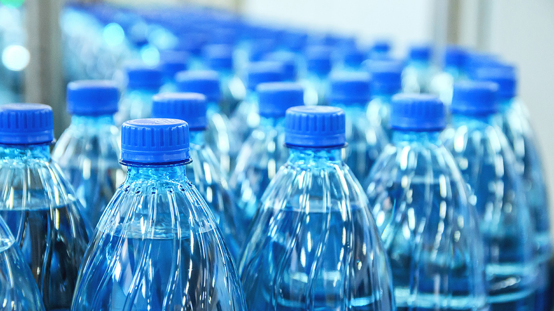 A close-up view of plastic water bottles on an assembly line.