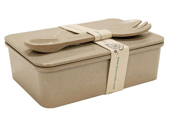 A food container made from rice husk. There is a eating utensil on top of the container.