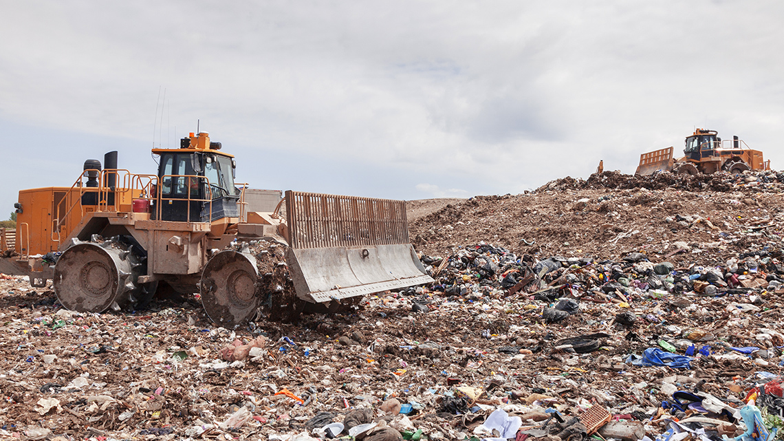 A landfill with two dozers moving garbage.
