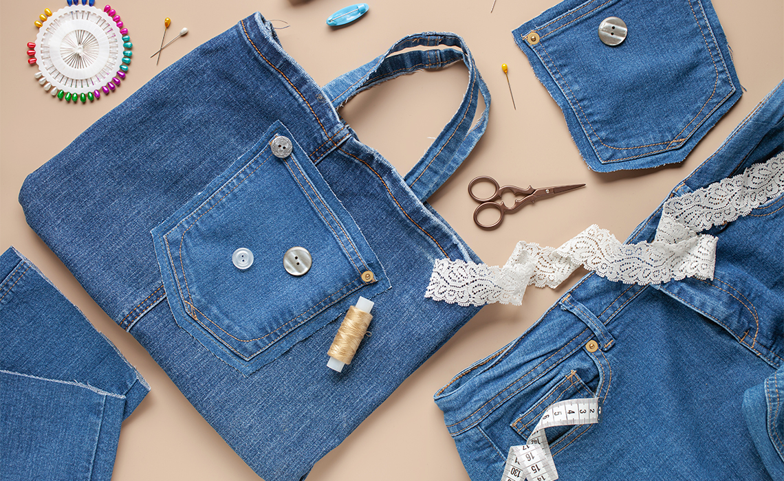 Top view of old scraps of jeans and a denim bag with sewing accessories.