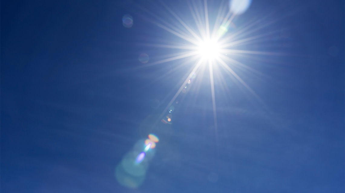 The sun shining in the clear blue sky.