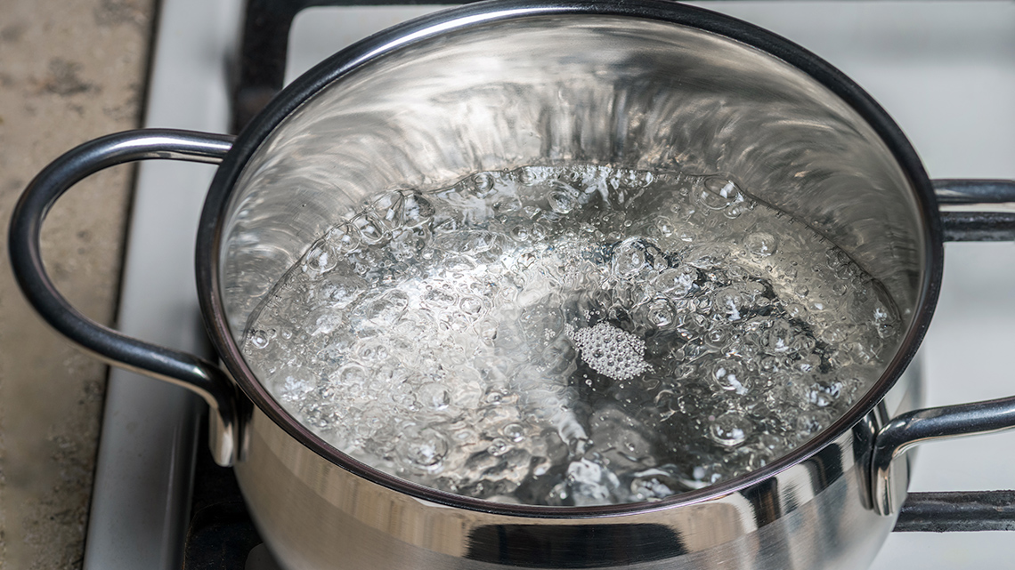 Water bubbling in a pot on a stove.