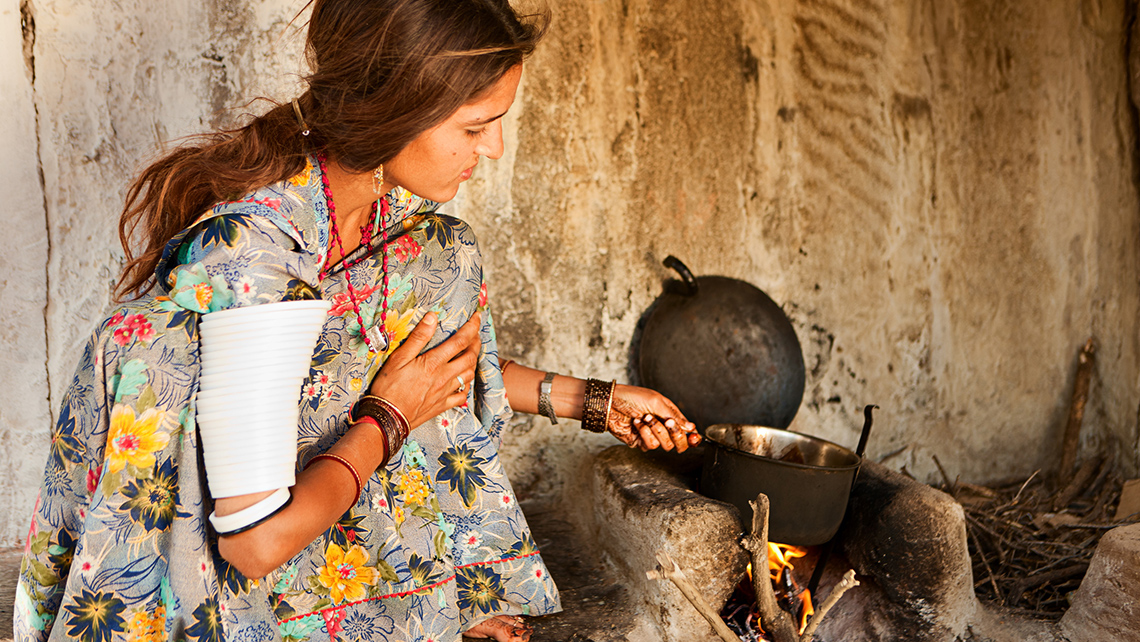 A person boiling water in a pan over a fire. 