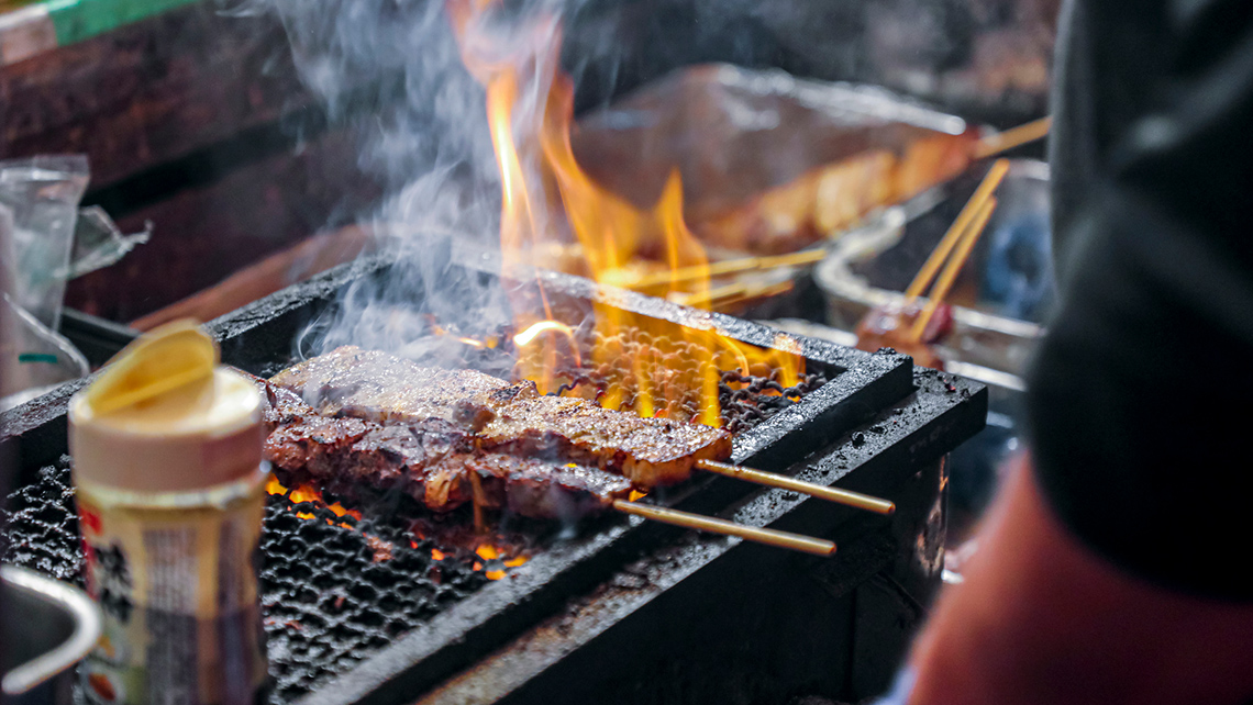 A person cooking food on a grate over an open fire. 