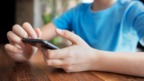 School age child holding a cell phone in their hands