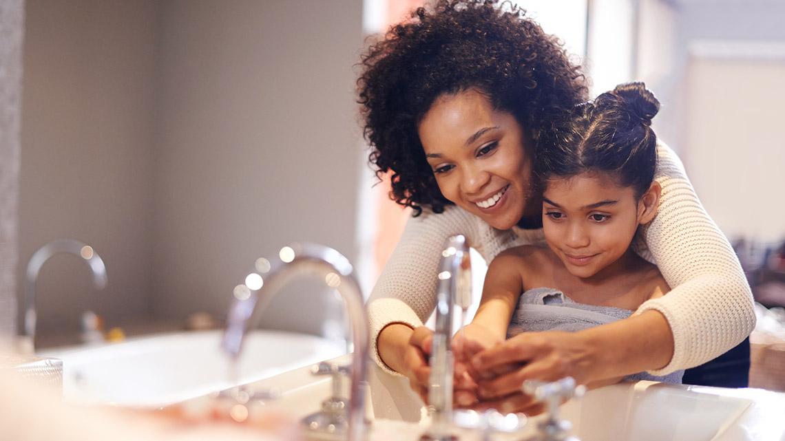 An adult and child washing their hands. 