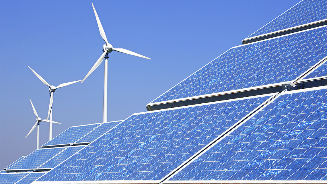 Solar panels with wind turbines in the background.