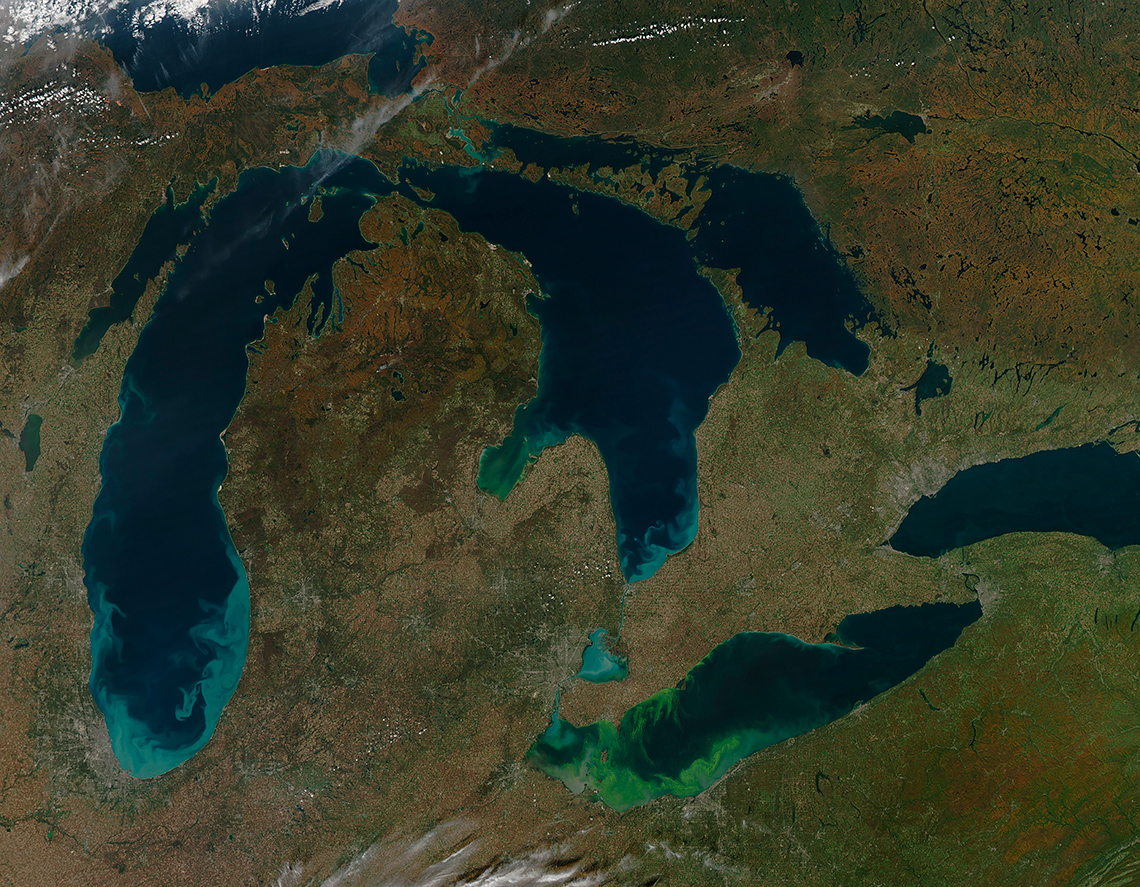 Satellite image of the Great Lakes with swirls of green colouring in Lake Erie and Lake Huron. These are blue-green algal blooms.