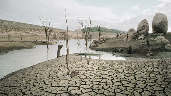A dried up dam with cracks in the extremely dry ground.