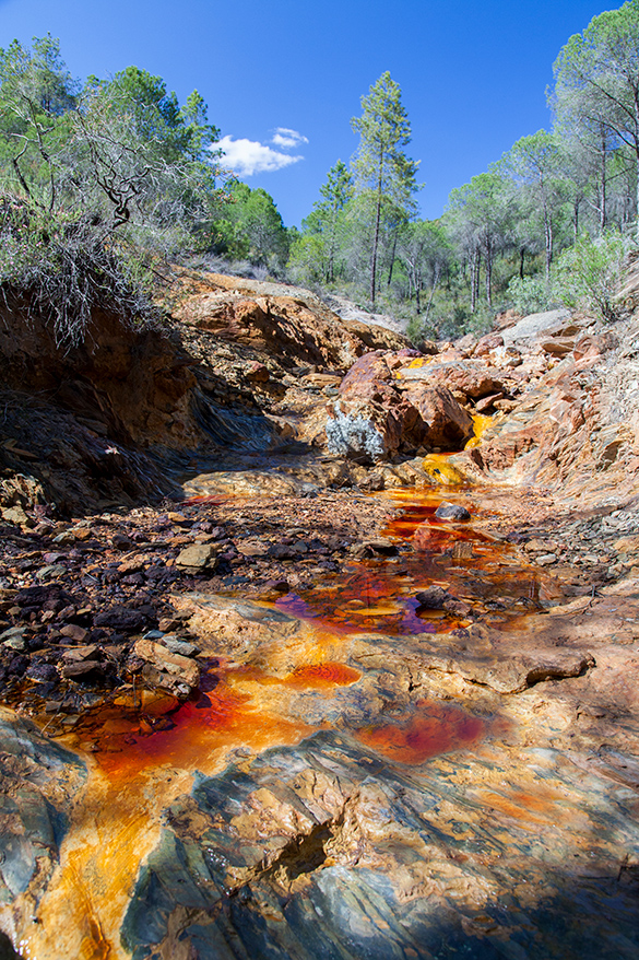 Water running down a river, the water is a red/brown colour.