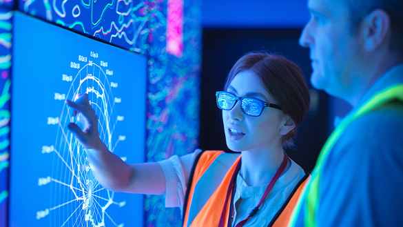 Two people examining a digital chart, while one person points to different values.