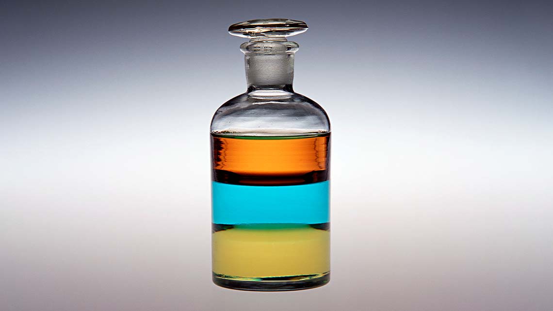 Three liquids that are all separated in one bottle. They are all resting on each other.