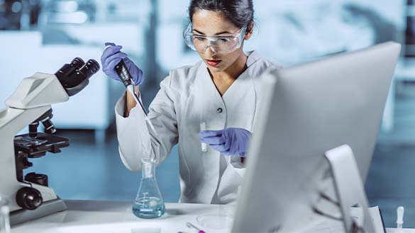 A person adding a substance to a beaker.