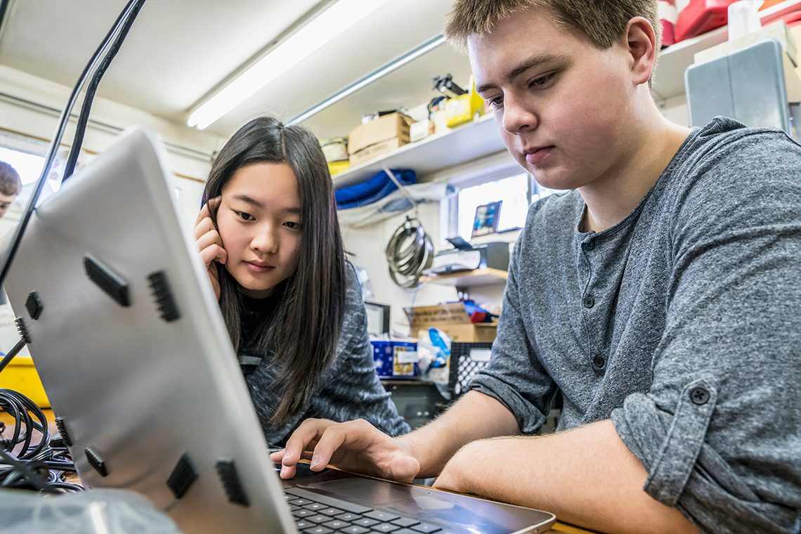 Two adolescent looking at a computer.