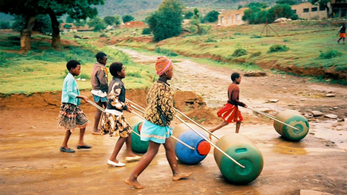 Children of different ages are pictured walking together and pushing hippo roller water collection devices.