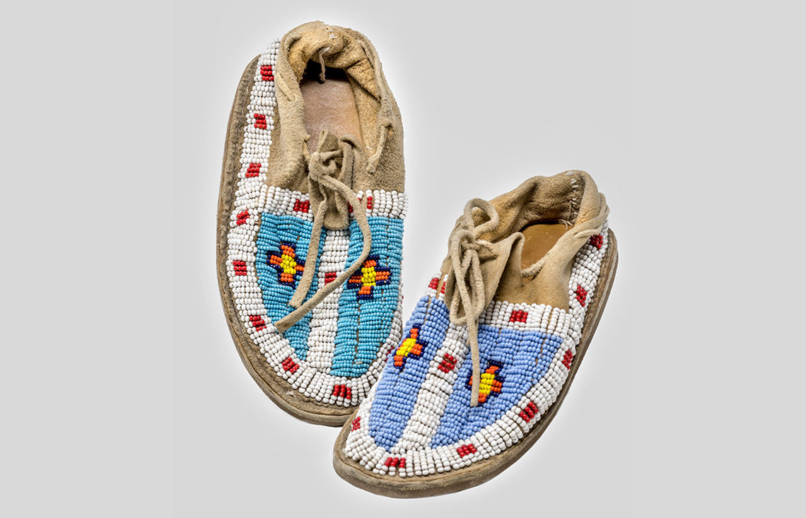 Moccasins made from leather and designed with intricate bead work along the top and sides.