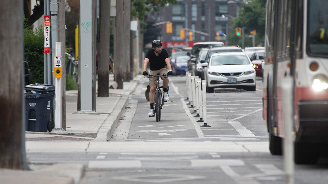 Biking A person biking along a bike lane on a busy road filled with cars and buses.