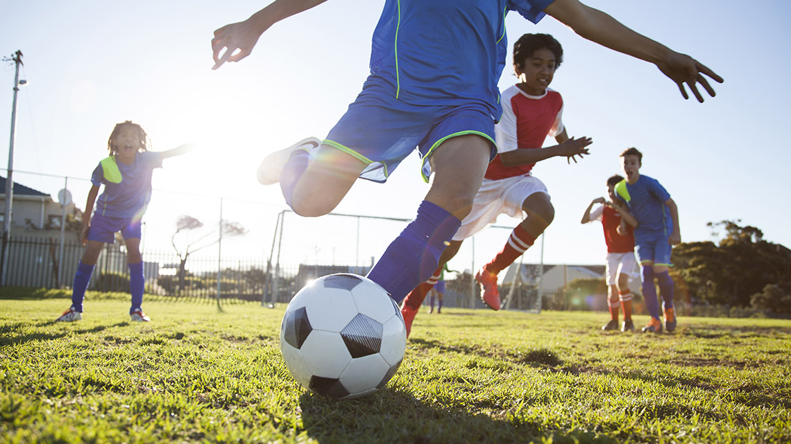 A group of learners playing soccer by moving the ball with their feet.