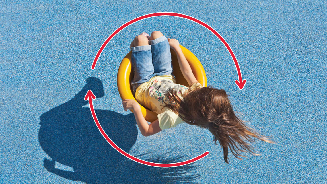A child sits in a saddle spinner at a playground. Two arrows show that it spins in a circle. 