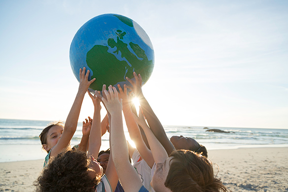 Learners are holding up a large globe together.