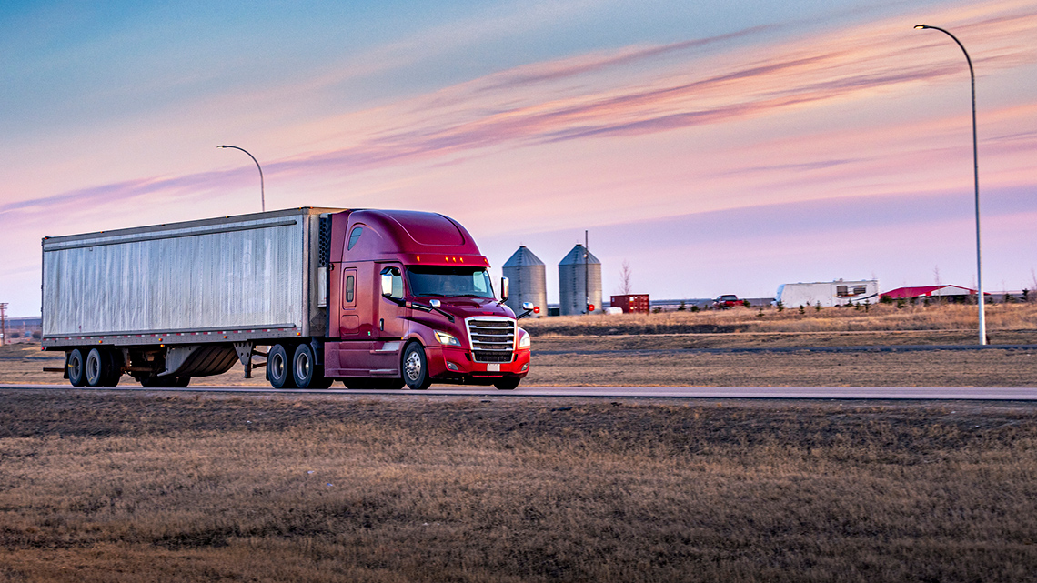 A truck driving on a road through farmland