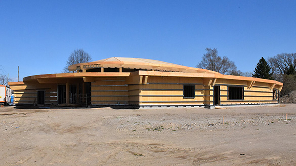 A turtle-shaped community centre being constructed with concrete, wood, and metal.