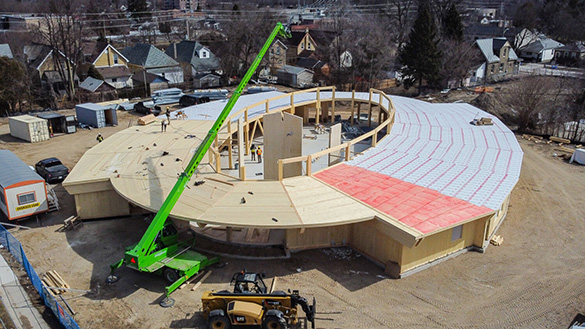 Aerial view of a crane and workers constructing a turtle-shaped community centre.