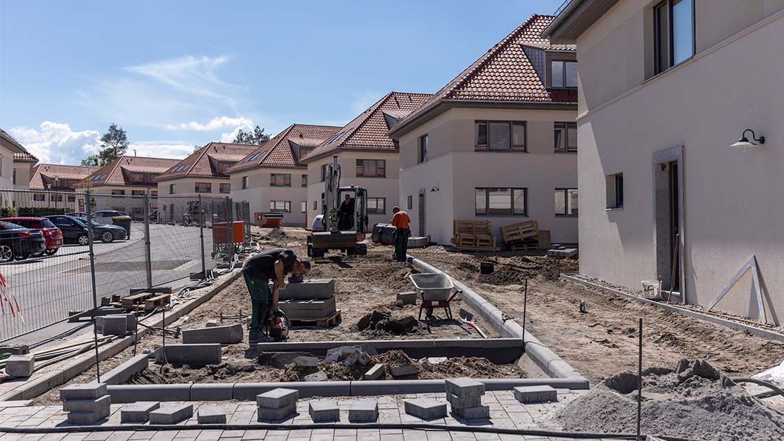 A team of workers using bricks to create pathways and other structures in a neighbourhood.