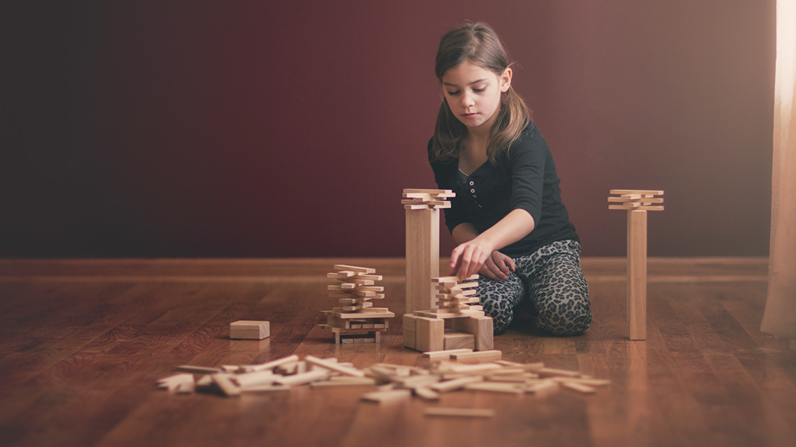 A child building a structure out of wooden blocks.