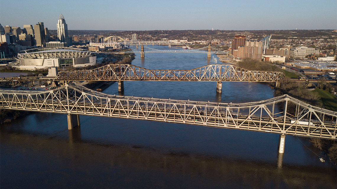 A bridge made up of steel beams in a triangular pattern has four lanes for traffic.