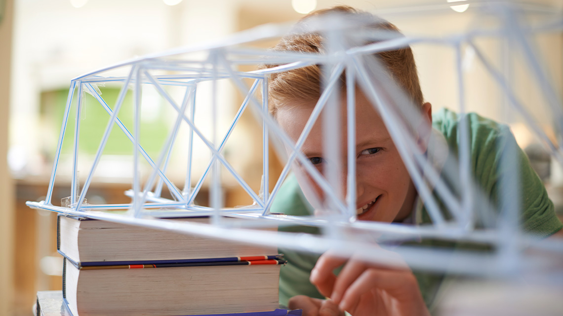 A learner creating a bridge out of straws.