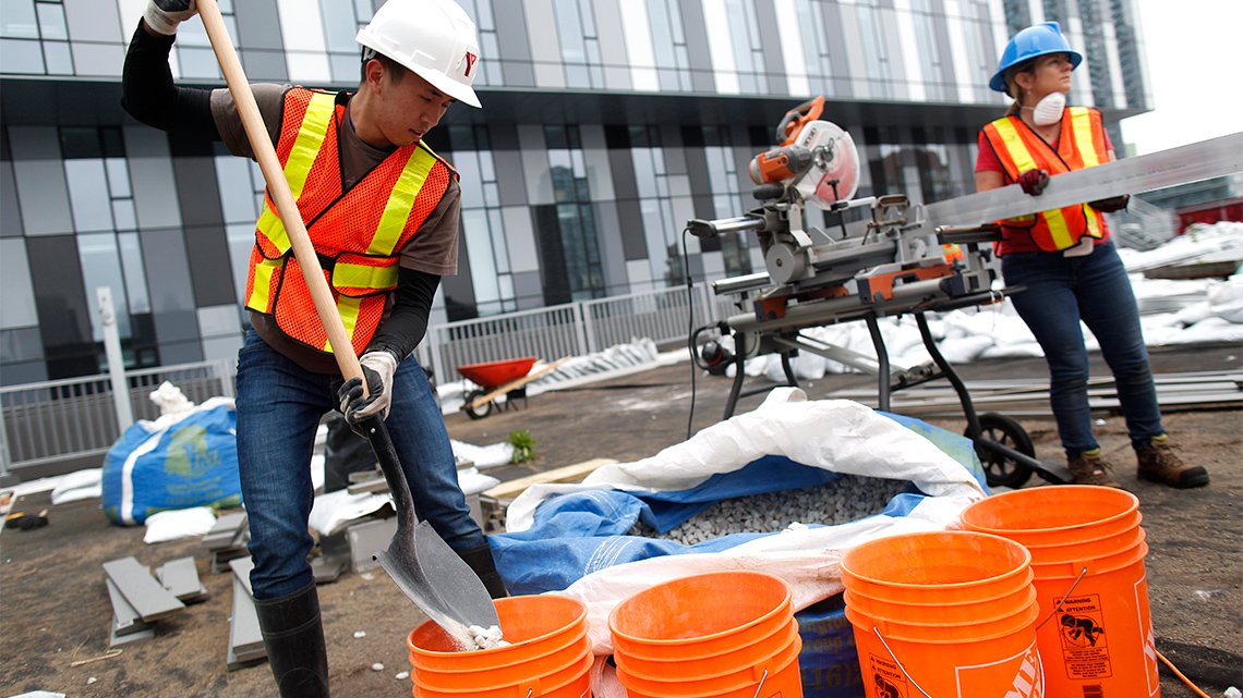 Volunteers shovel gravel and soil on to the roof.