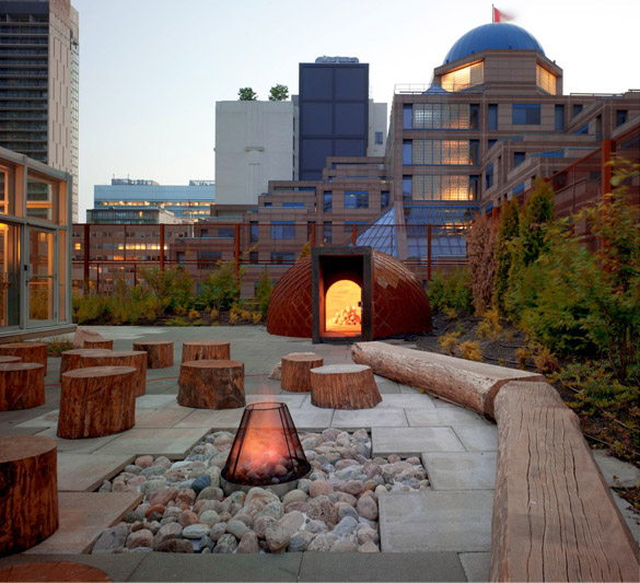 NCFS Toronto A rooftop with a fire pit surrounded by tree stumps and logs for sitting.