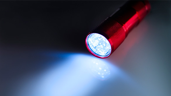 Flashlight shining A flashlight on the ground shining its light across the floor.