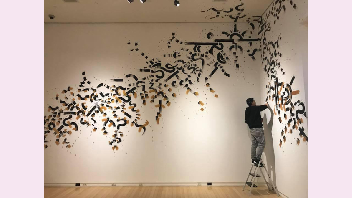A painting titled Eras of Jazz: The Visual by Reyes Padilla. It is painted on a wall with black and gold lines and circles and squiggles.