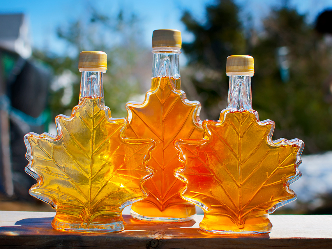 Three maple-leaf shaped bottles of maple syrup.