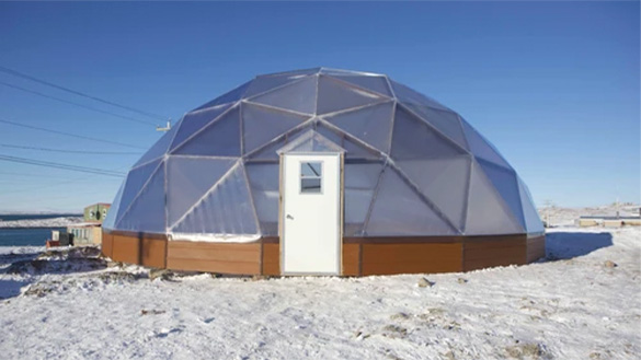 A geodesic dome made up of triangular panels and a central door sits in snow in the arctic.