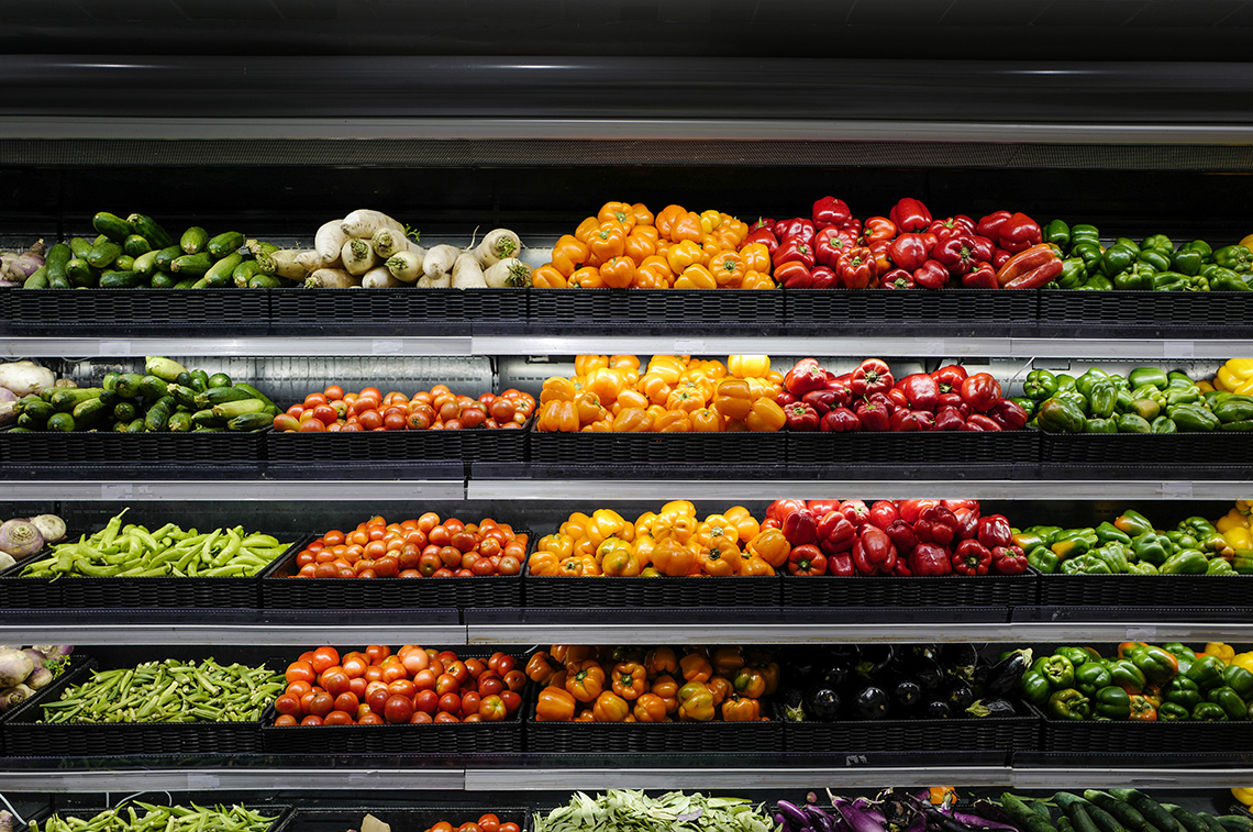 Multiple shelves of vegetable produce at a supermarket.