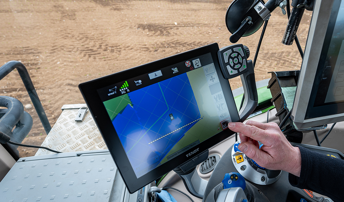 A farmer drives a tractor with a GPS steering system in a field and applies crop protection products.