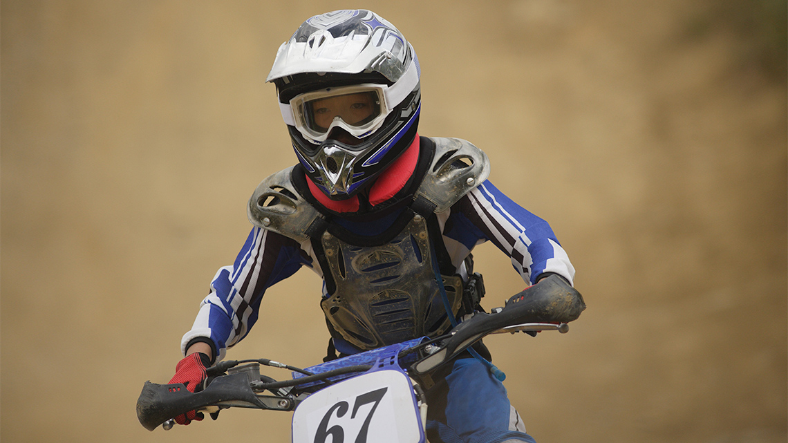 Person with helmet and googles getting ready for a dirt bike race.