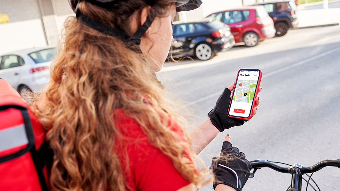 A person on a bike with a smartphone in their hand checking a route with GPS.