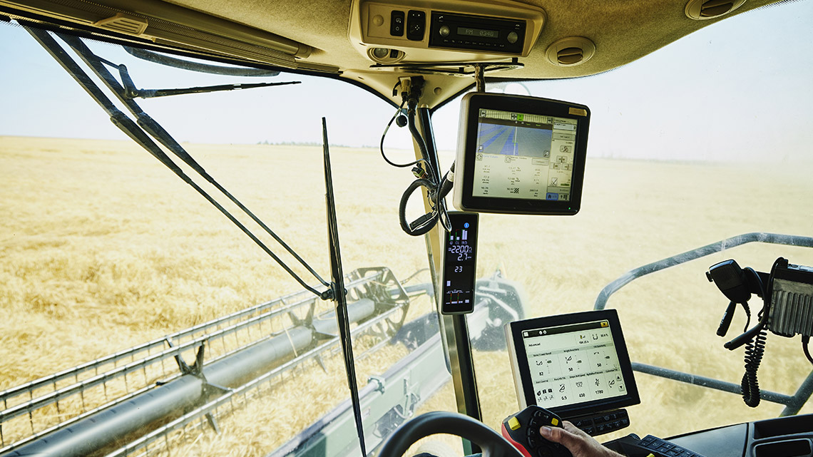 An agricultural vehicle. In the seating area there are two computers set up and a smartphone attached to the dashboard as well.
