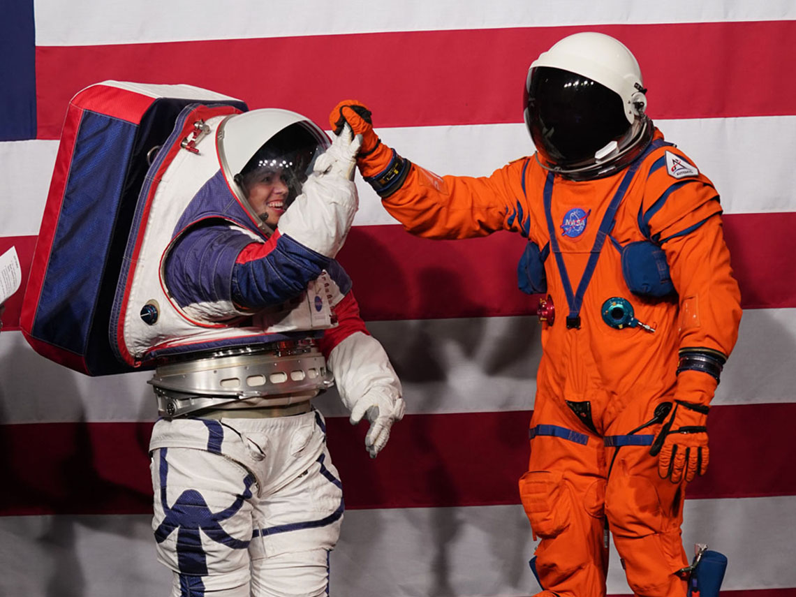 Two possible designs of a future spacesuit: one that is white and quite bulk with a large backpack, and the other is orange and very light.