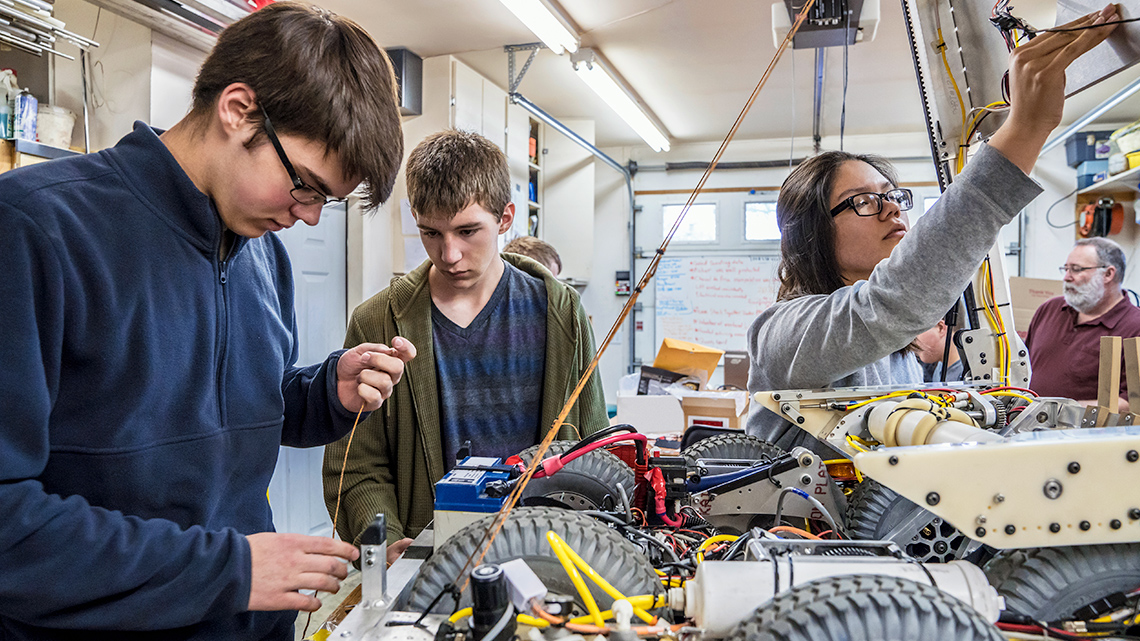 Students building various electrical components using wires and other tools.