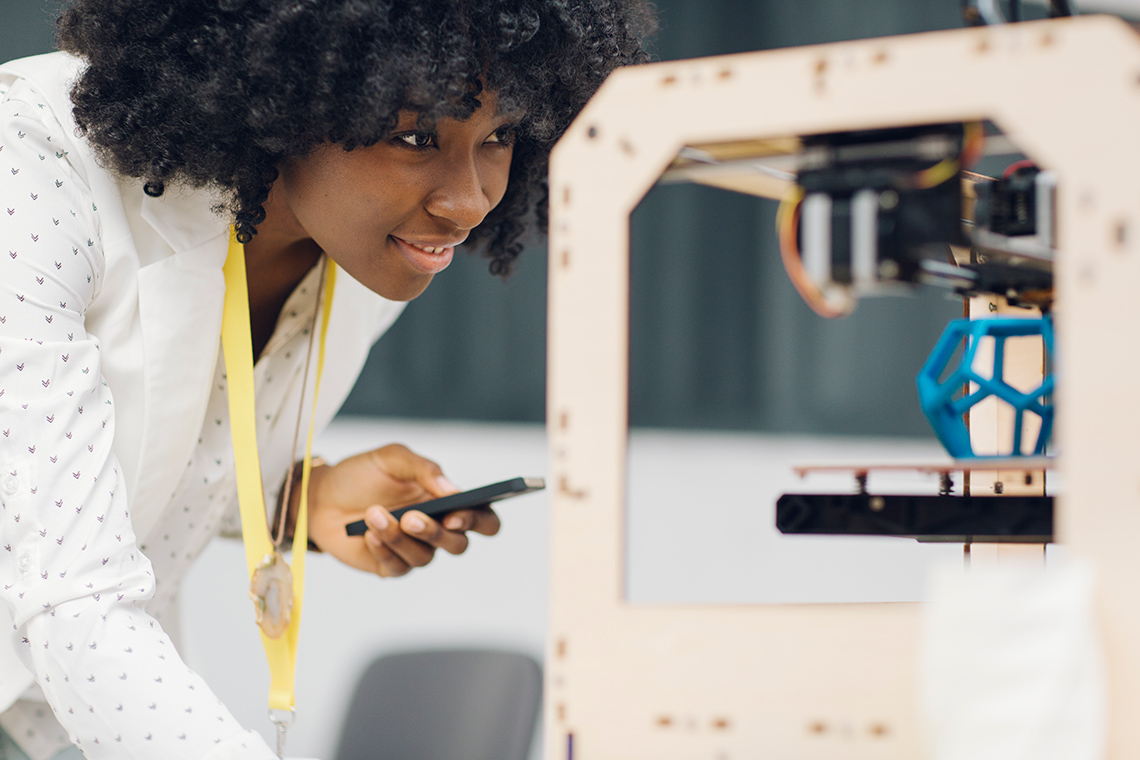 An engineer observes a 3D printer creating their design.