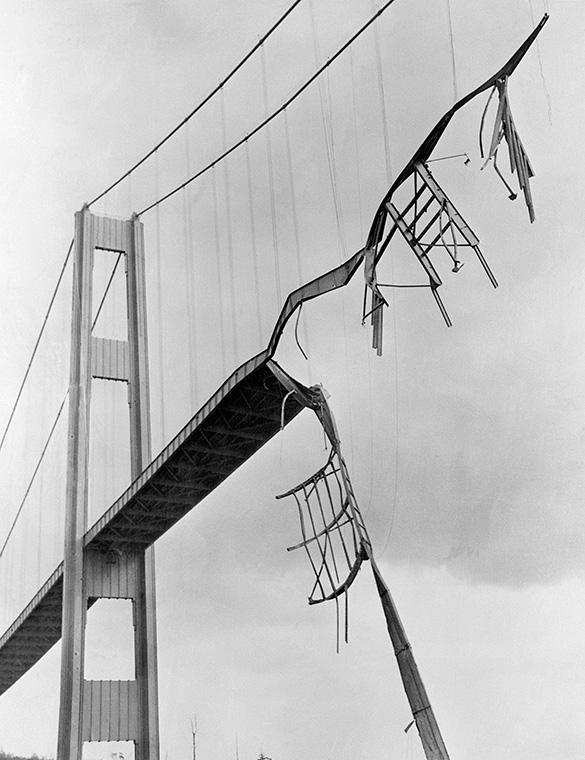 A suspension bridge with a large portion collapsed and hanging from wires.