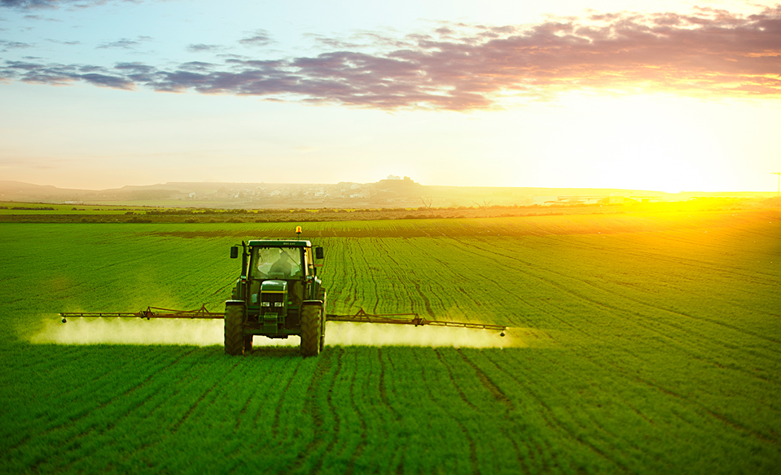 A tractor spraying fertilizer on crops.